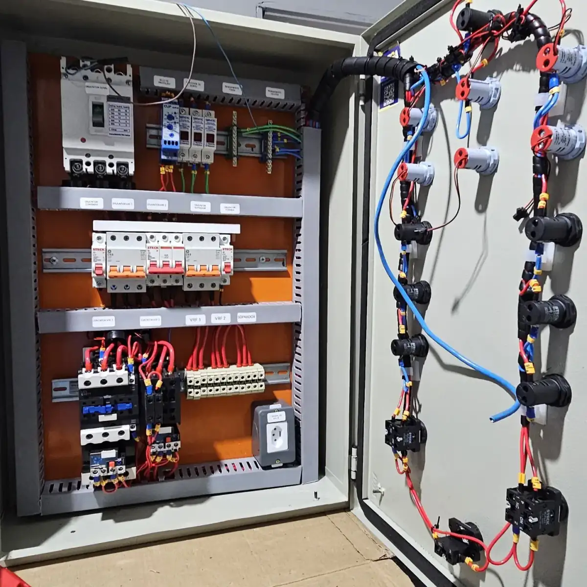 Quadro elétrico aberto e montado: disjuntor geral, minidisjuntores, contatores com relés térmicos e porta com sinaleiros e botoeiras já cabeados