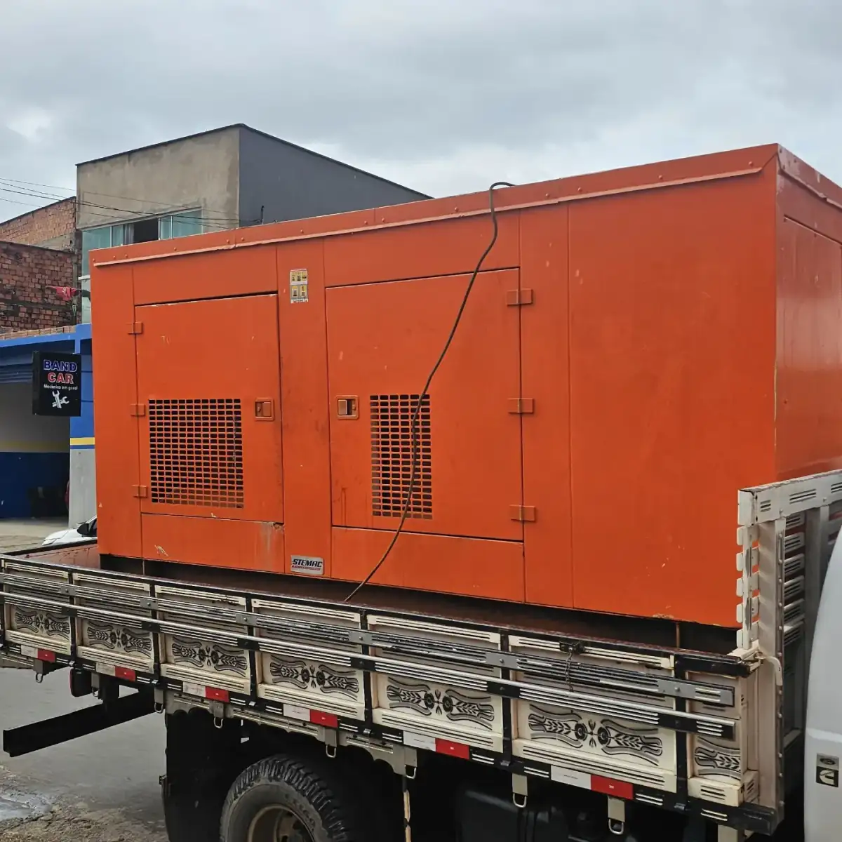 Grupo gerador carenado laranja de 370 kVA sobre a carroceria de caminhão para entrega