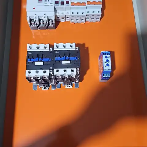 Contatores e relé de monitoramento posicionados na placa de montagem laranja