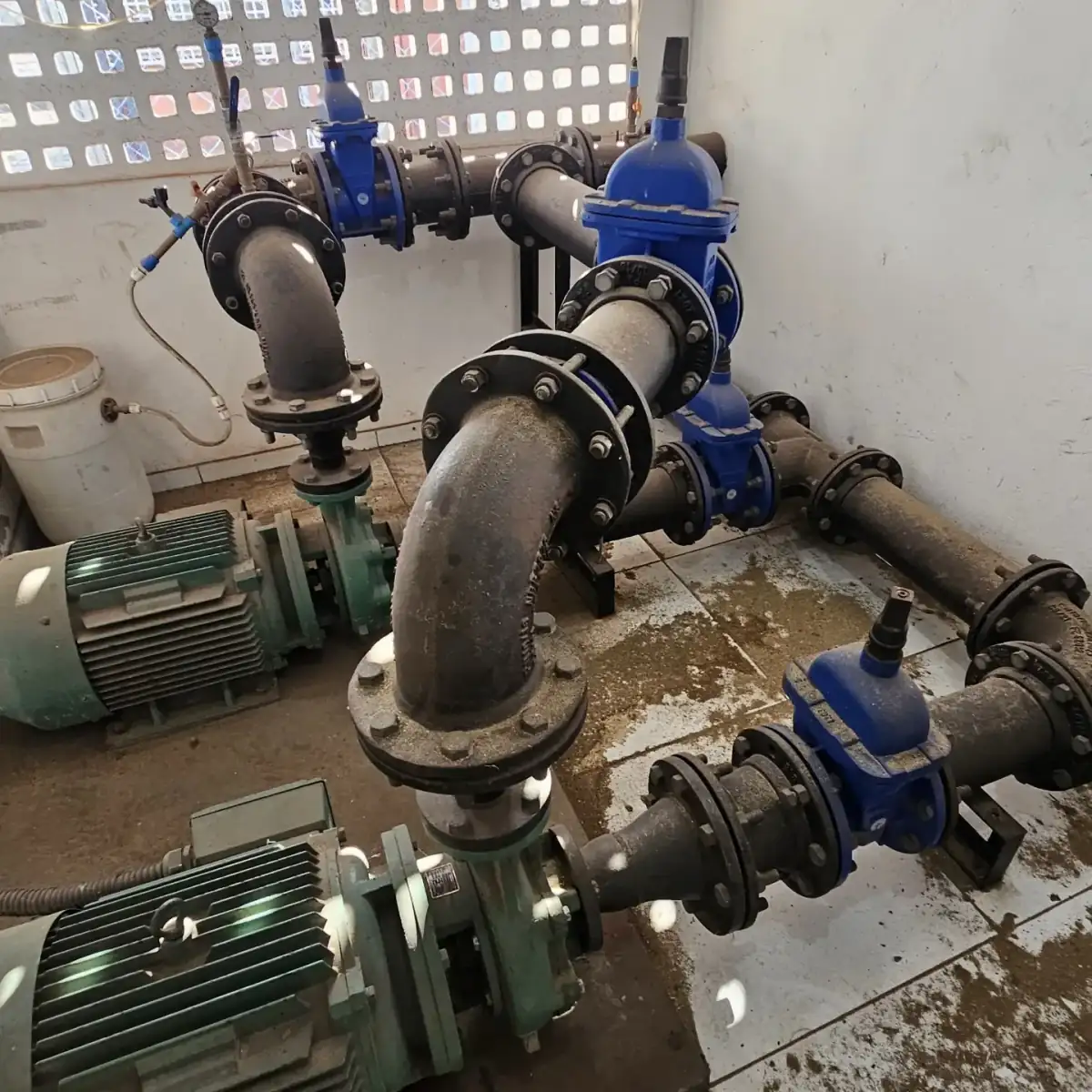 Casa de bombas do sistema de água com motobombas e registros azuis